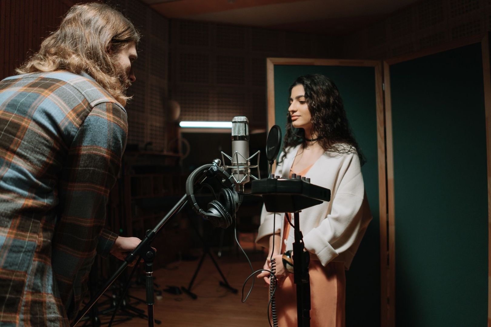 Zwei Personen arbeiten mit Mikrofon im Tonstudio an einer Musikaufnahme